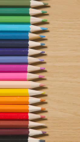 Vertical-Video-Of-Coloured-Pencils-Arranged-In-A-Line-On-Wooden-Background